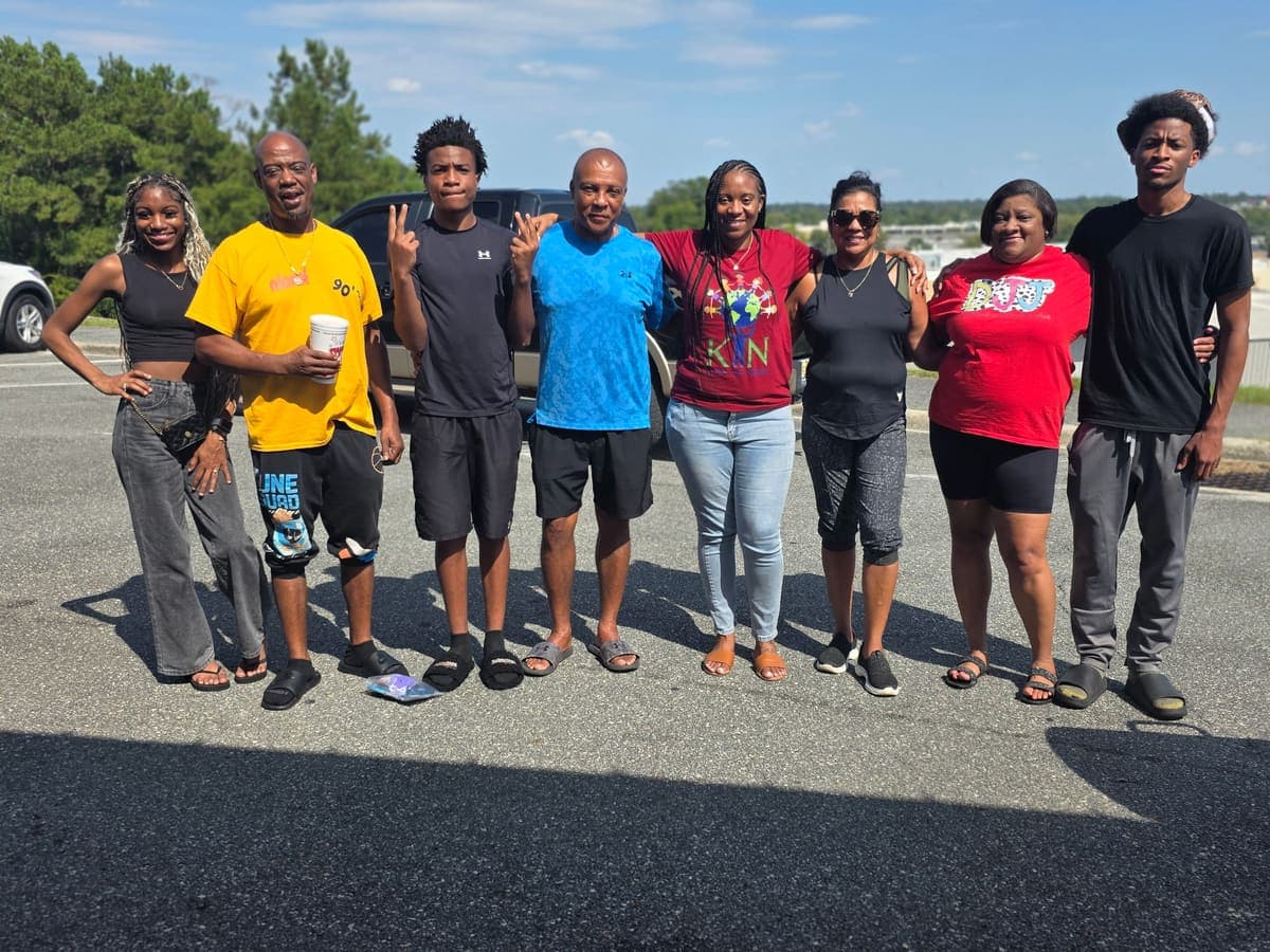 A line of volunteers and community members posing together in the parking lot
