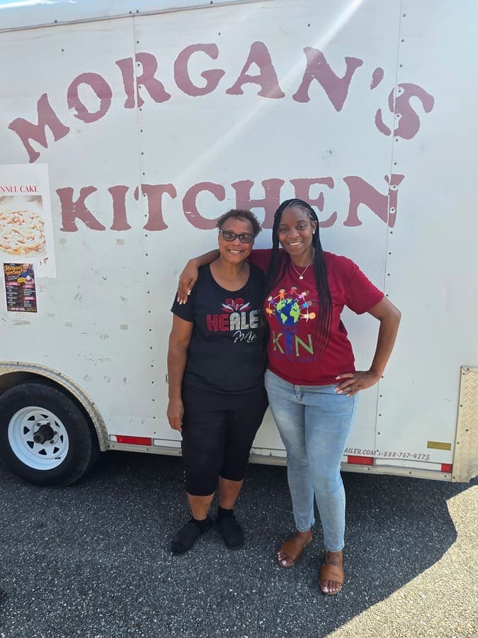 K.I.N. volunteer with a vendor in front of the Morgan's Kitchen food trailer