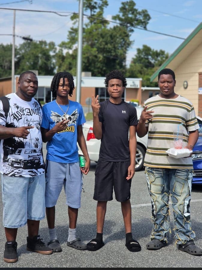 Four young men posing together at the park