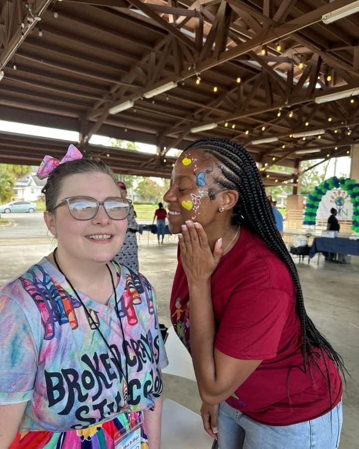 Face painter and a young girl with a freshly painted face