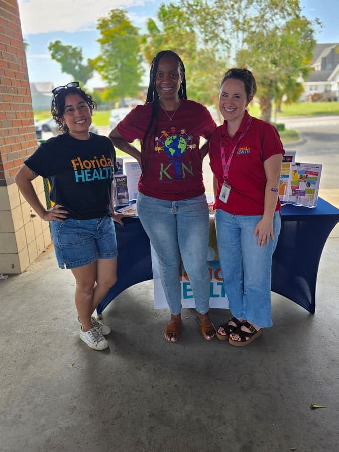 Three women at a community vendor table