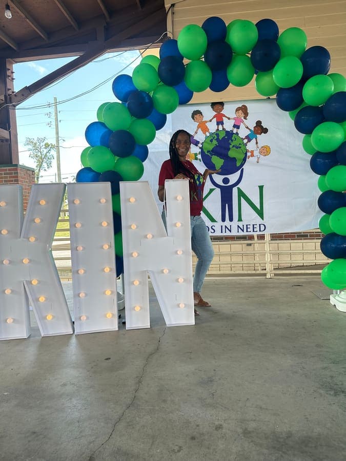 Lighted K.I.N. marquee letters beside the balloon arch under the pavilion