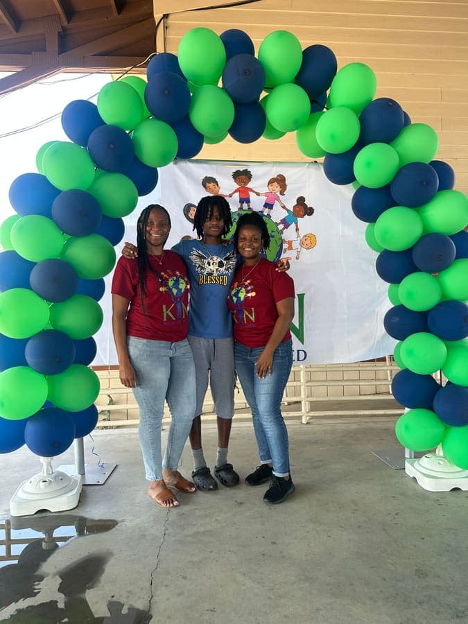 Family posing under the balloon arch in front of the K.I.N. backdrop