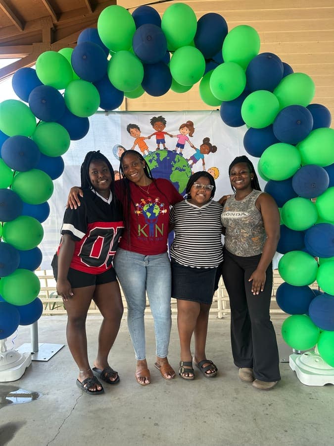 Group of women and girls posing under the balloon arch