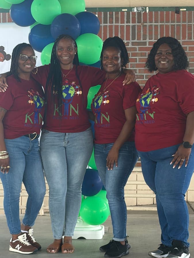 Four K.I.N. volunteers in matching K.I.N. shirts
